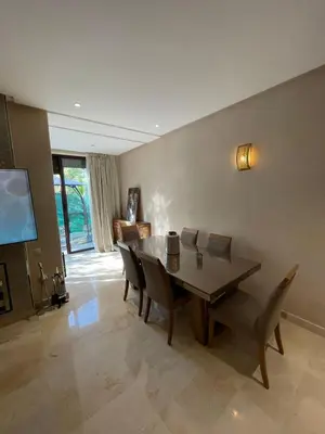 a dining room with a table and chairs and a tv at villa jardin de l'Atlas in Marrakech