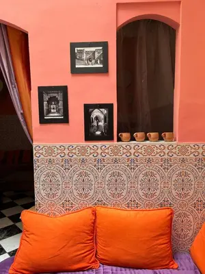 a room with an orange pillow and a wall with pictures at Riad Sofia signature in Marrakech
