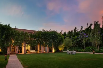 a house with a green yard with trees and chairs at Pavillon Terra Ababila en Exclusivité in Marrakech