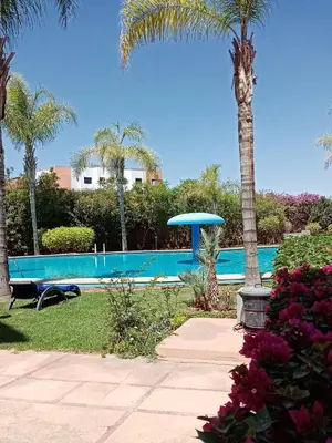 a swimming pool with a palm tree and a blue umbrella at HERMINIE ATLAS in Marrakech