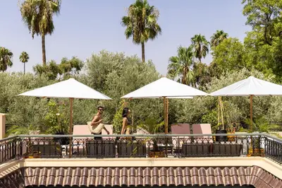 a man and woman sitting under umbrellas at a pool at Riad LAZ Mimoun & Spa in Marrakech