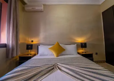 a bedroom with a bed with a yellow pillow on it at Harmony Inn Entire 2 bedroom apartment in Marrakech