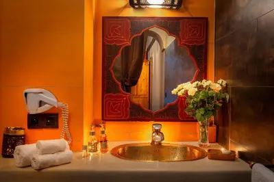 a bathroom with a sink and a mirror and flowers at Riad Rodaina & SPA in Marrakech