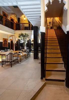 a staircase in a building with tables and chairs at Riad Rodaina & SPA in Marrakech