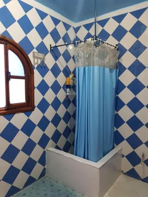 a shower with a blue shower curtain in a bathroom at Maison style riad aux chants des oiseaux in Marrakech