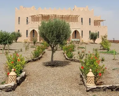 a building with a tree and flowers in front of it at Riad Nohad Marrakech Villa Privatisée in Oulad Boudene