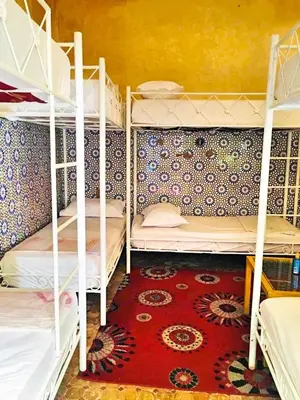 a room with three bunk beds and a red carpet at Riad Dia in Marrakech