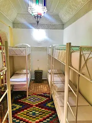 a room with three bunk beds and a chandelier at Riad Dia in Marrakech