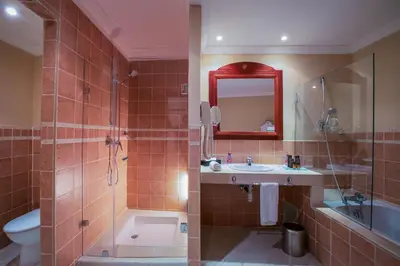a bathroom with a sink and a toilet and a mirror at Grand Mogador Agdal & Spa in Marrakech