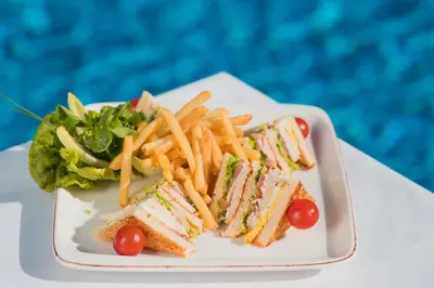 a plate with a sandwich and french fries and a salad at Grand Mogador Agdal & Spa in Marrakech
