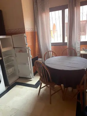 a kitchen with a table and chairs and a refrigerator at Appartement dans résidence avec piscine in Marrakech
