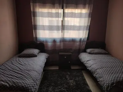two beds in a small room with a window at Appartement dans résidence avec piscine in Marrakech