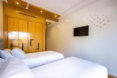two beds in a room with a tv on the wall at NEW! Appartement de luxe emplacement idéal Gueliz in Marrakech