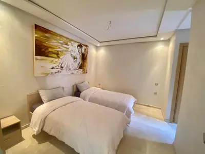 a bedroom with two beds and a painting on the wall at APPARTEMENT CARRE EDEN in Marrakech