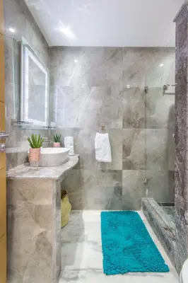 a bathroom with a sink and a shower with a blue rug at NEW! Gueliz,Terrasse, Fibre optique, IPTV in Marrakech