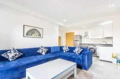 a living room with a blue couch and a kitchen at NEW! Gueliz,Terrasse, Fibre optique, IPTV in Marrakech