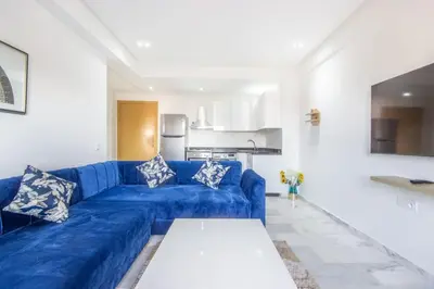 a living room with a blue couch and a kitchen at NEW! Gueliz,Terrasse, Fibre optique, IPTV in Marrakech
