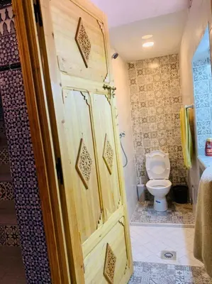 a bathroom with a toilet and a wooden door at Maison 211 in Marrakech