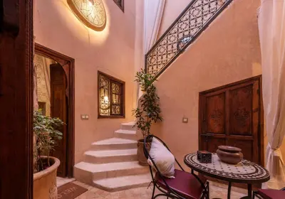 a hallway with stairs and a table and chairs at Riad Oumnia - Top emplacement - Riad en entier - Jacuzzi in Marrakech