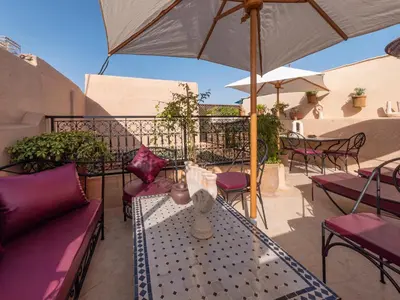 a patio with tables and chairs and an umbrella at Riad Oumnia - Top emplacement - Riad en entier - Jacuzzi in Marrakech