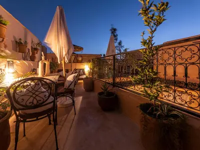 a balcony with a table and chairs and plants at Riad Oumnia - Top emplacement - Riad en entier - Jacuzzi in Marrakech
