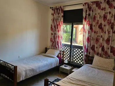 a bedroom with two beds and a window with curtains at atlas golf resort marrakech 