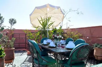 a patio with a table and chairs and an umbrella at Riad La Perle de Marrakech in Marrakech