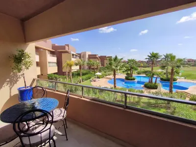 a balcony with a table and chairs and a view of a pool at Prestigia Marrakech Dar Cheryana in Marrakech