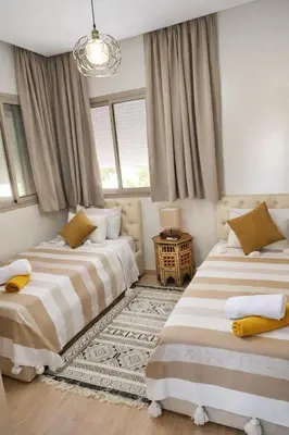two beds in a room with two windows at Prestigia Marrakech Dar Cheryana in Marrakech