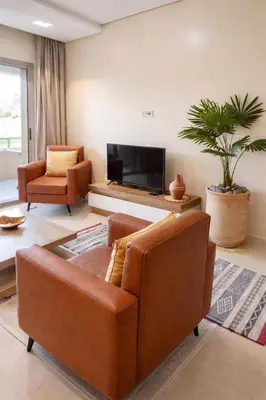 a living room with two leather chairs and a flat screen tv at Prestigia Marrakech Dar Cheryana in Marrakech