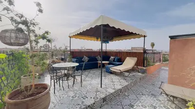 a patio with a blue couch under an umbrella at Riad dar Rbati in Marrakech