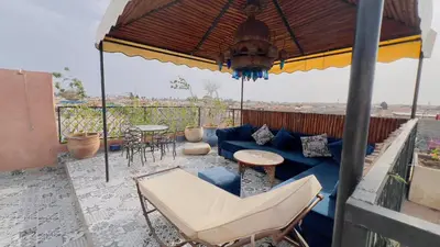 a patio with a blue couch and chairs and an umbrella at Riad dar Rbati in Marrakech