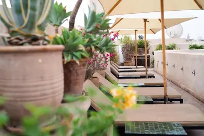 a row of tables with potted plants and an umbrella at Riad Al Massarah in Marrakech