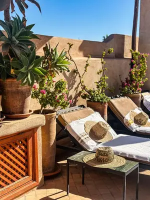 a patio with potted plants and a table with hats on it at Riad Al Massarah in Marrakech