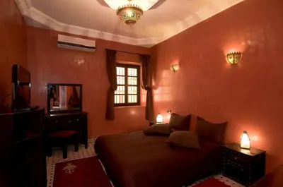 a bedroom with a bed and a tv and a window at RIAD Le MINASDAM in Marrakech