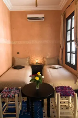 two beds in a room with a table and two chairs at RIAD Le MINASDAM in Marrakech