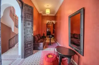 a hallway with orange walls and a chair and a mirror at RIAD Le MINASDAM in Marrakech