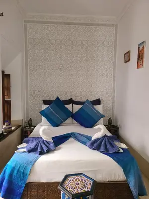 a bedroom with a large bed with blue pillows at Riad Parfum d'Orient in Marrakech