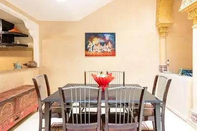 a dining room table with chairs and a red flower on it at Riad Anir in Marrakech