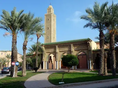 a building with a clock tower and palm trees at Riad Anir in Marrakech
