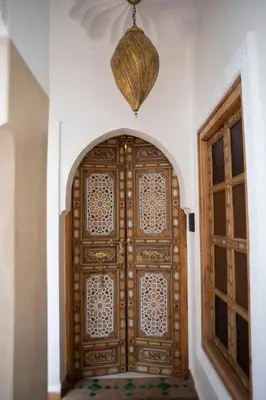 a large wooden door in a room with two windows at Riad Dar Fanny in Marrakech