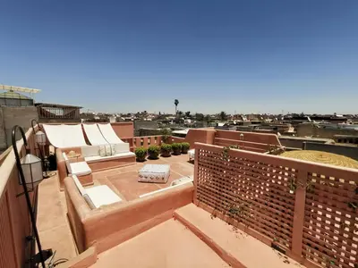 a balcony with a couch and chairs on a roof at The Douiria in Marrakech