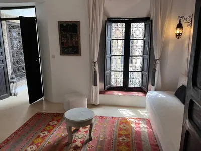 a bedroom with a bed and a stool and a window at RIAD ENNAFOURA BOUTIQUE HOTEL in Marrakech