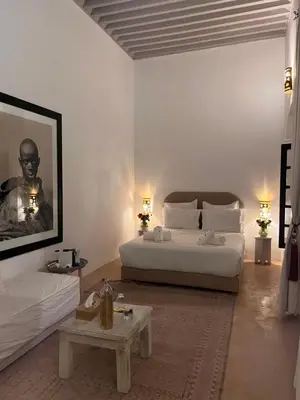 a white bedroom with a bed and a coffee table at RIAD ENNAFOURA BOUTIQUE HOTEL in Marrakech