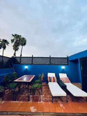 a patio with a table and chairs and a blue wall at Archduke private rooms in Marrakech