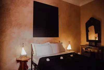 a bedroom with a bed with two lamps and a mirror at Riad Bensaid in Marrakech