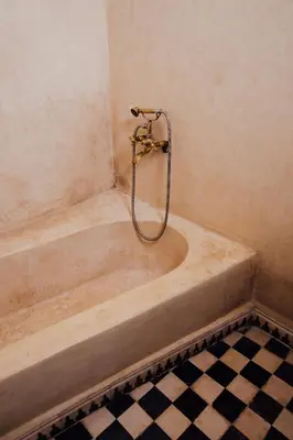 a bath tub with a shower in a bathroom at Riad Bensaid in Marrakech