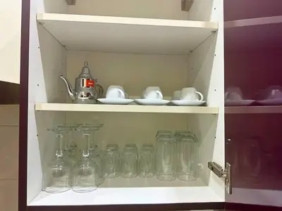 a cabinet filled with glass jars and a teapot at Appartement Marrakech avec piscine in Marrakech