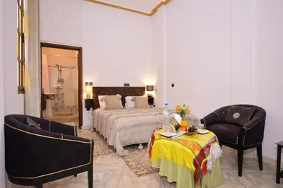 a bedroom with a bed and two chairs and a table at RYAD RDATE LWALIDINE in Marrakech