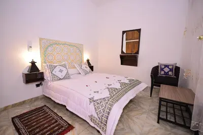a bedroom with a bed and a table and a chair at RYAD RDATE LWALIDINE in Marrakech
